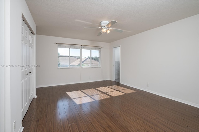 empty room with ceiling fan, dark hardwood / wood-style flooring, and a textured ceiling