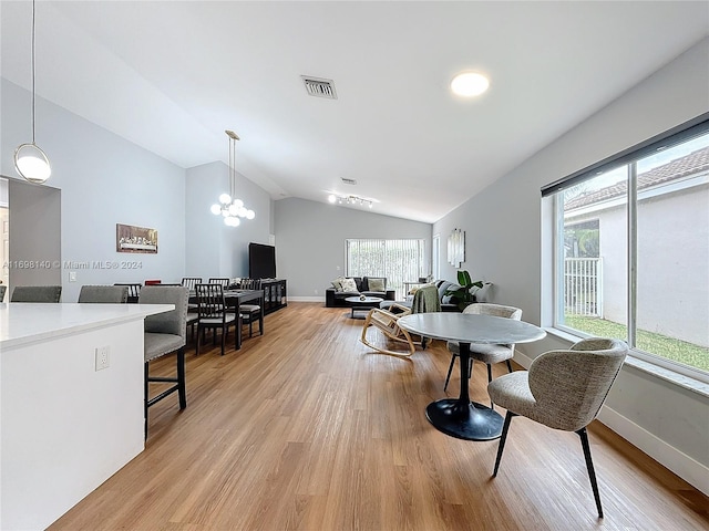 dining area with light hardwood / wood-style flooring, vaulted ceiling, and a notable chandelier