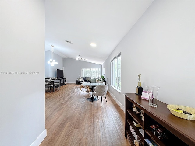 office with a notable chandelier, light wood-type flooring, and vaulted ceiling