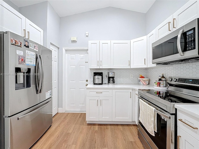 kitchen featuring lofted ceiling, light hardwood / wood-style floors, white cabinetry, and appliances with stainless steel finishes