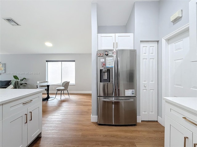 kitchen with stainless steel fridge, white cabinets, and light wood-type flooring