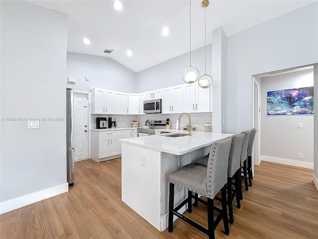 kitchen featuring sink, a breakfast bar area, decorative light fixtures, kitchen peninsula, and stainless steel appliances