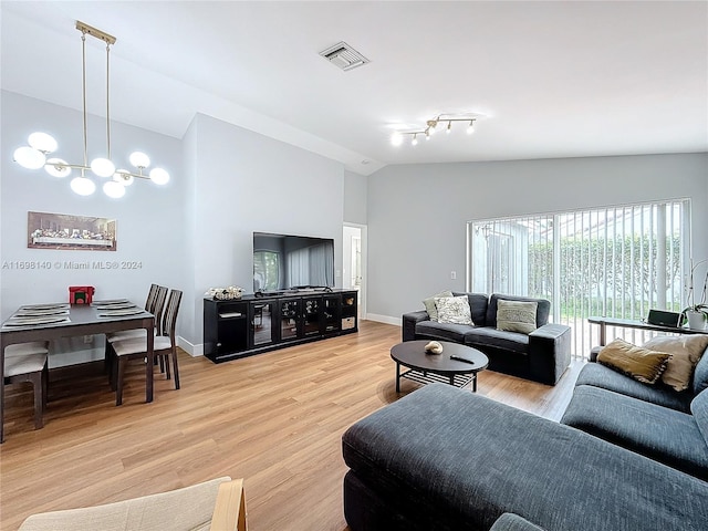 living room featuring light wood-type flooring, track lighting, vaulted ceiling, and a notable chandelier