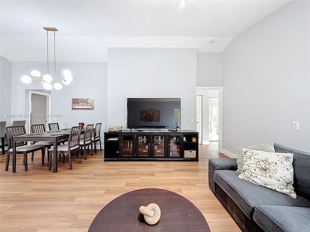 living room with a notable chandelier, light hardwood / wood-style floors, and vaulted ceiling