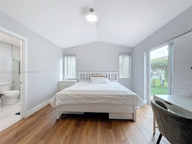 bedroom with ensuite bath, vaulted ceiling, and light wood-type flooring