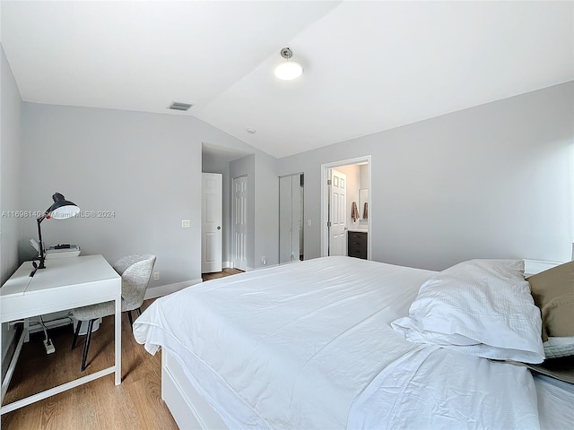 bedroom featuring ensuite bathroom, wood-type flooring, and lofted ceiling