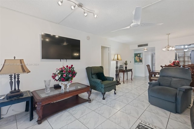 living room with a textured ceiling and ceiling fan with notable chandelier