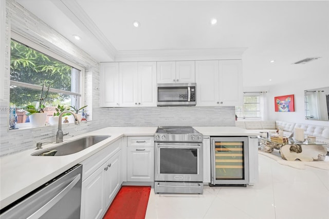 kitchen featuring white cabinets, wine cooler, sink, and appliances with stainless steel finishes