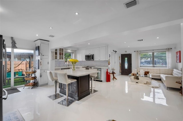 kitchen with white cabinetry, tasteful backsplash, wine cooler, a kitchen bar, and a kitchen island