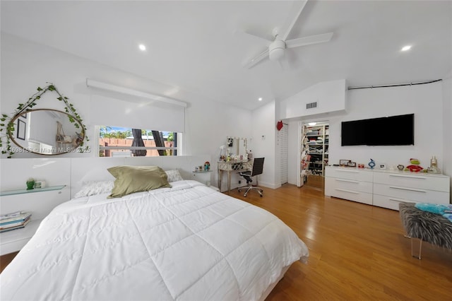 bedroom featuring vaulted ceiling, ceiling fan, light wood-type flooring, a spacious closet, and a closet