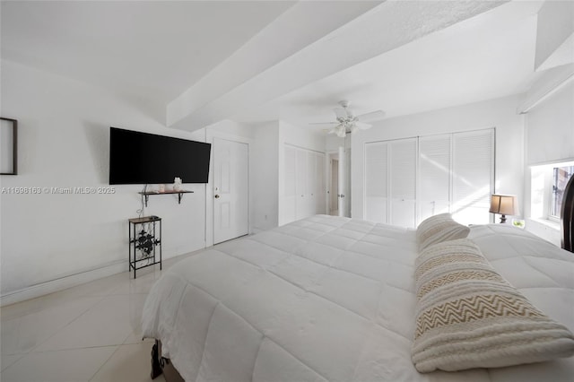 tiled bedroom with ceiling fan and two closets