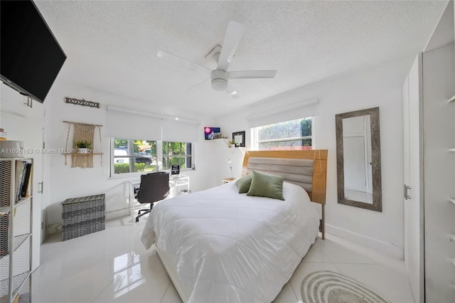 tiled bedroom featuring ceiling fan, a textured ceiling, and multiple windows