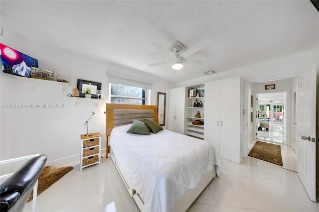 tiled bedroom with ceiling fan and a textured ceiling