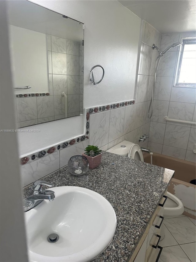 full bathroom with vanity, toilet, tiled shower / bath, and tile walls