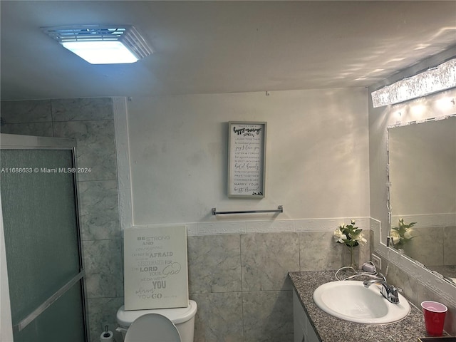 bathroom featuring vanity, toilet, and tile walls