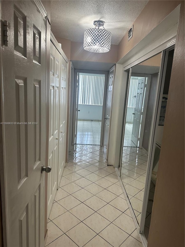 corridor featuring light tile patterned floors and a textured ceiling