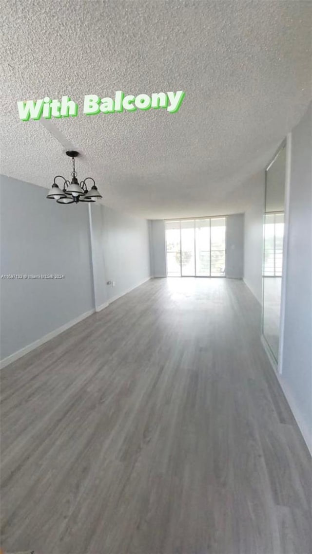 unfurnished room with a textured ceiling, hardwood / wood-style flooring, and a wealth of natural light