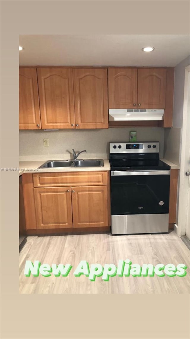 kitchen with stainless steel electric range oven, light hardwood / wood-style flooring, and sink