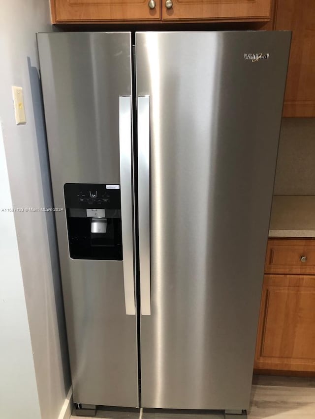 room details with stainless steel refrigerator with ice dispenser and light wood-type flooring