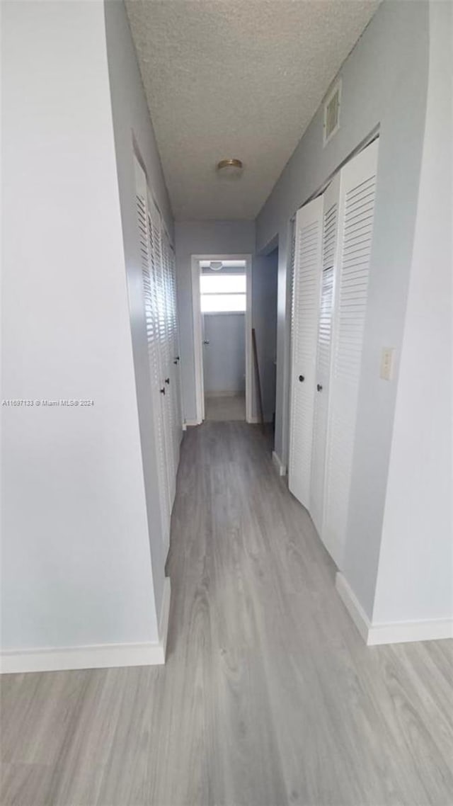 corridor featuring a textured ceiling and light wood-type flooring