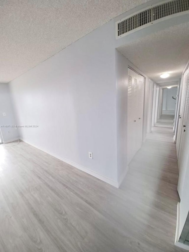 unfurnished room featuring a textured ceiling and light wood-type flooring