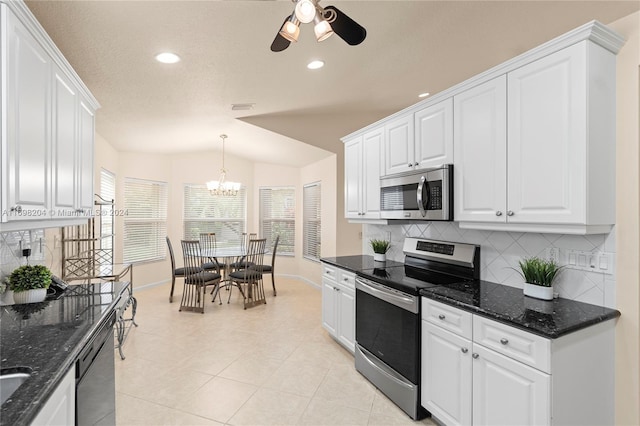 kitchen with white cabinetry, stainless steel appliances, backsplash, dark stone countertops, and pendant lighting