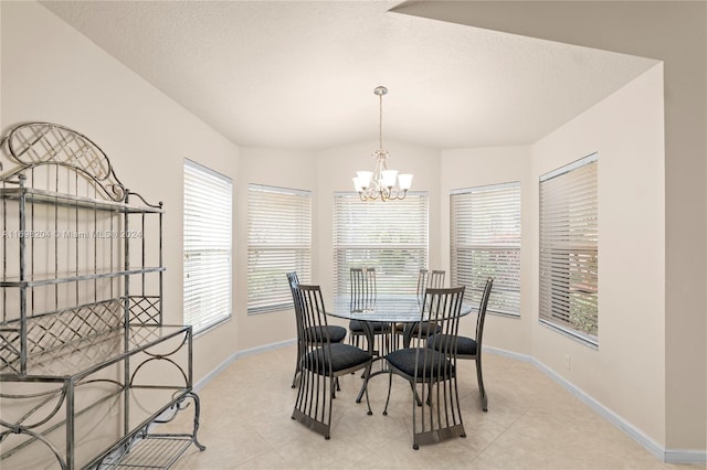 dining area with light tile patterned flooring, a textured ceiling, and an inviting chandelier