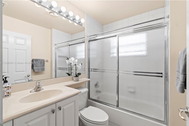 full bathroom with shower / bath combination with glass door, vanity, and toilet