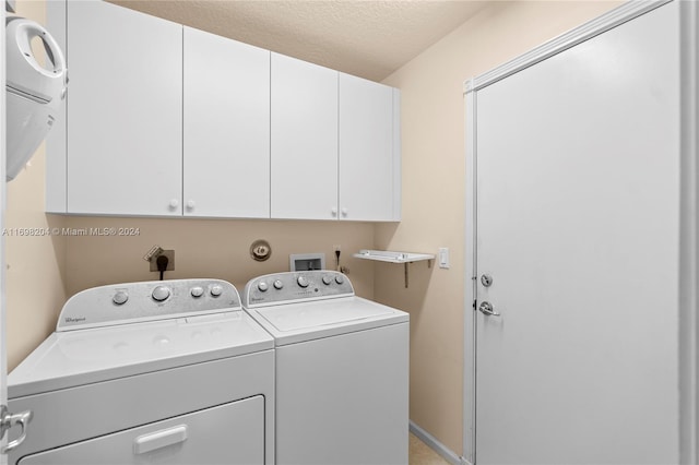 laundry room featuring washer and dryer, a textured ceiling, and cabinets