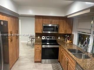 kitchen featuring sink, stainless steel appliances, tasteful backsplash, light hardwood / wood-style floors, and stone countertops