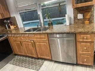 kitchen with sink, stainless steel dishwasher, and stone countertops