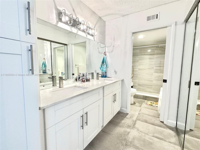 full bathroom featuring visible vents, toilet, a textured ceiling, a shower stall, and a sink