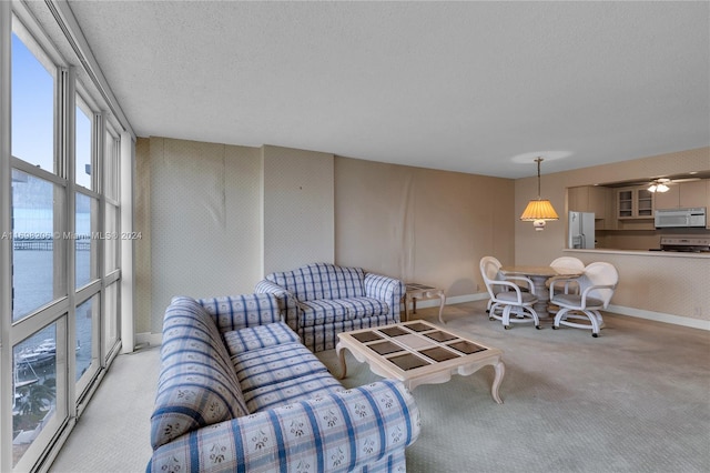 carpeted living room with a textured ceiling, a water view, and ceiling fan