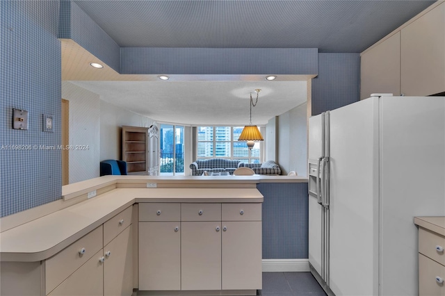 kitchen with kitchen peninsula, dark tile patterned flooring, pendant lighting, and white refrigerator with ice dispenser