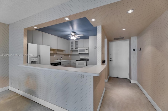 kitchen featuring light carpet, kitchen peninsula, white appliances, ceiling fan, and white cabinets