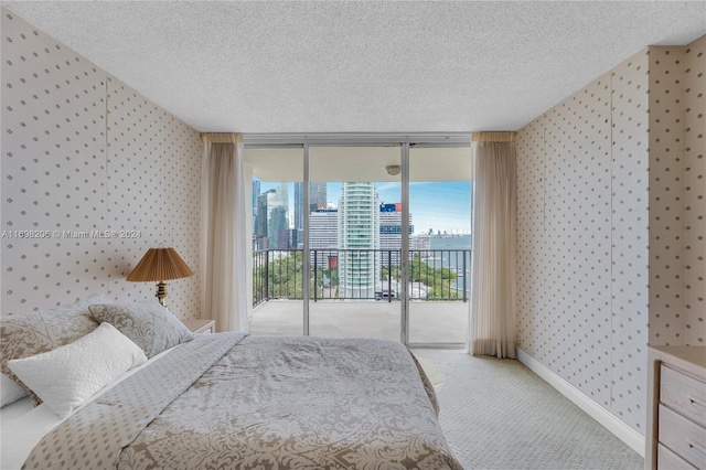 carpeted bedroom featuring a textured ceiling, access to outside, and a wall of windows