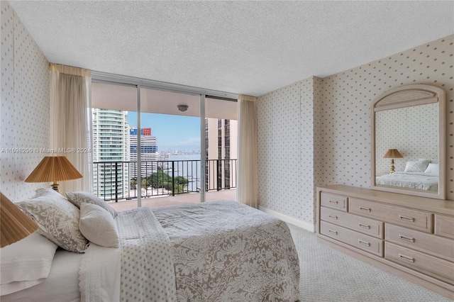 bedroom with carpet flooring, a wall of windows, a textured ceiling, and access to outside