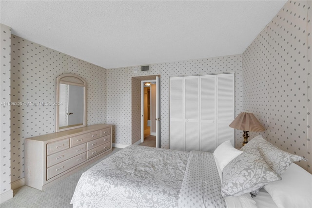 bedroom featuring a textured ceiling, light carpet, and a closet