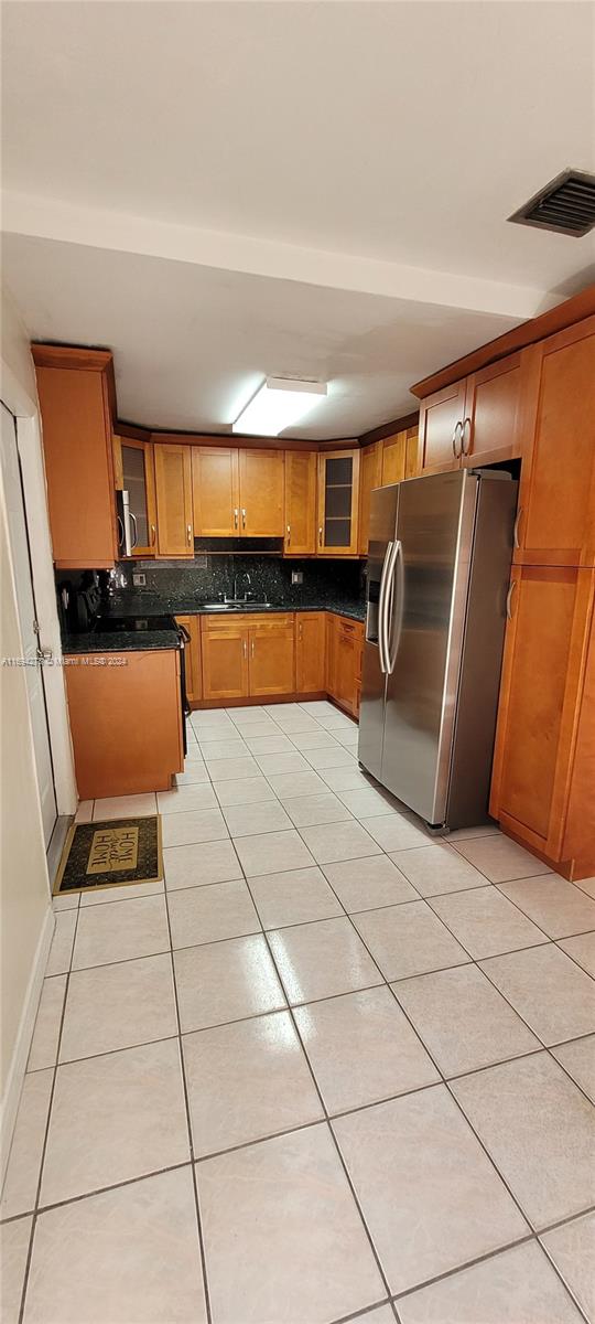 kitchen with stainless steel fridge with ice dispenser, tasteful backsplash, light tile patterned floors, and sink