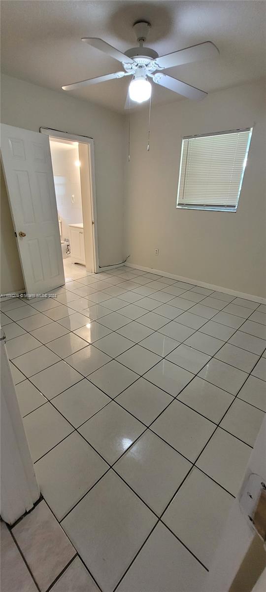 tiled empty room featuring ceiling fan