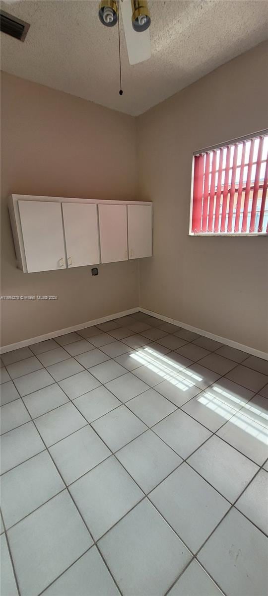 tiled empty room featuring ceiling fan and a textured ceiling