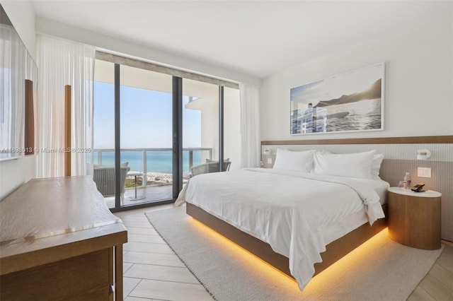 2201 Collins Ave Unit 1015, Miami Beach, FL 33139 - bedroom featuring access to exterior, a water view, light wood-type flooring, and wainscoting