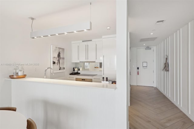 2201 Collins Ave Unit 1015, Miami Beach, FL 33139 - kitchen with white cabinetry, light countertops, a peninsula, a sink, and pendant lighting
