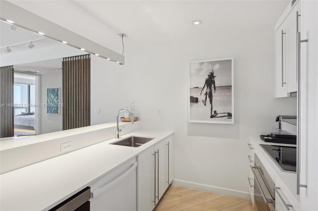 2201 Collins Ave Unit 1015, Miami Beach, FL 33139 - kitchen with a sink, wall oven, black electric stovetop, white cabinets, and light wood finished floors