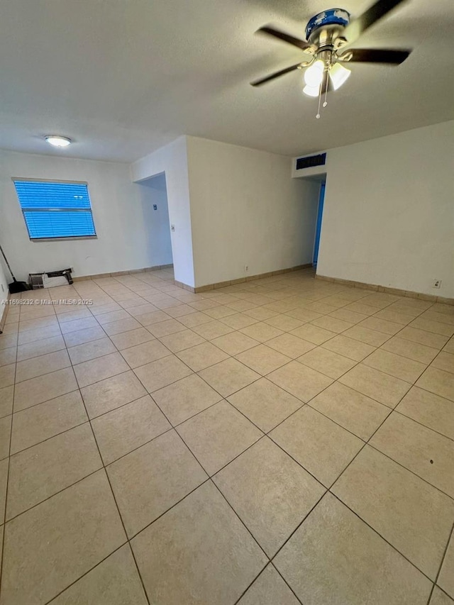 empty room featuring light tile patterned floors, baseboards, and a ceiling fan