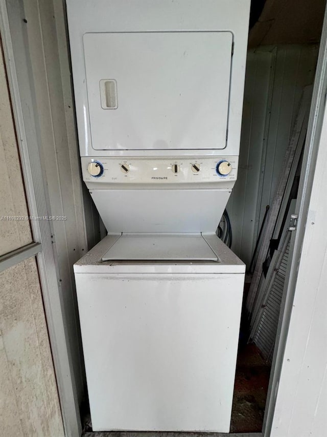 washroom featuring laundry area, wood walls, and stacked washing maching and dryer