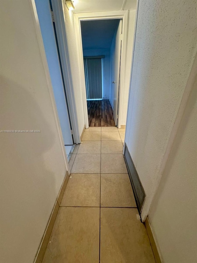 hallway featuring light tile patterned floors and baseboards