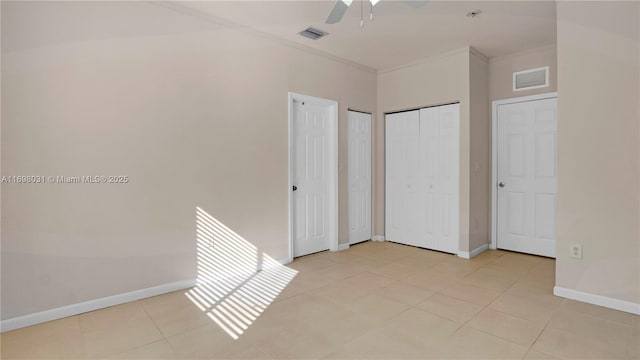 unfurnished bedroom with ceiling fan, ornamental molding, and two closets