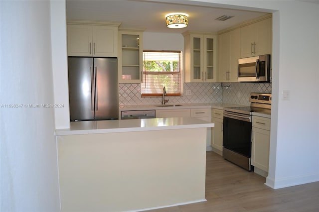 kitchen featuring decorative backsplash, appliances with stainless steel finishes, light hardwood / wood-style floors, and sink