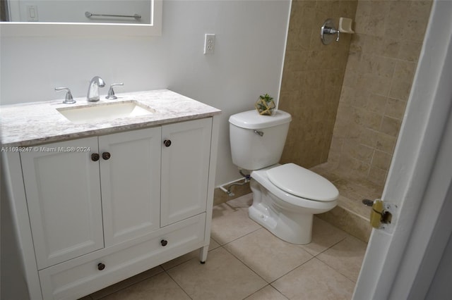 bathroom with tile patterned floors, vanity, a tile shower, and toilet